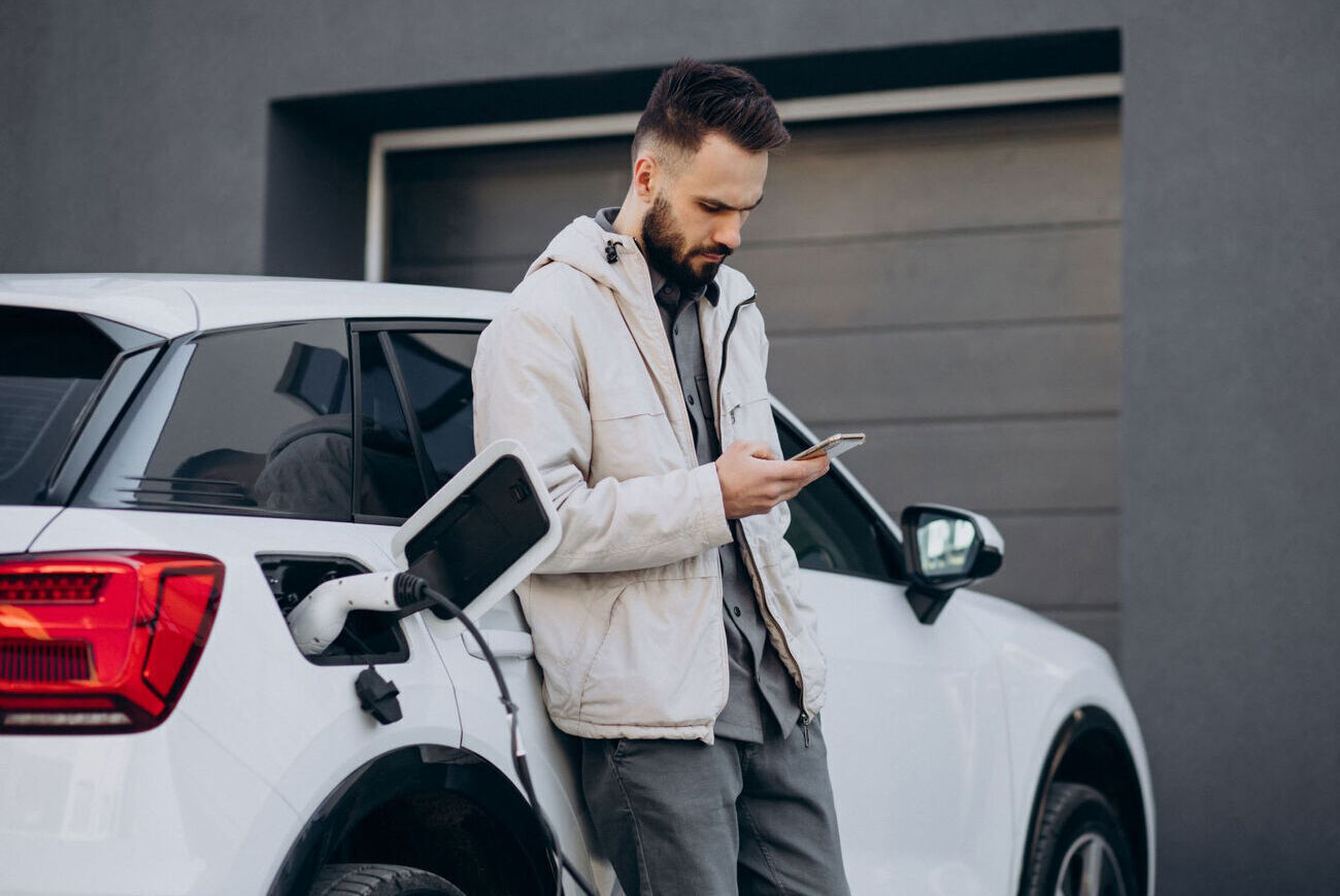 Mann steht an einem Auto, das aufgeladen wird